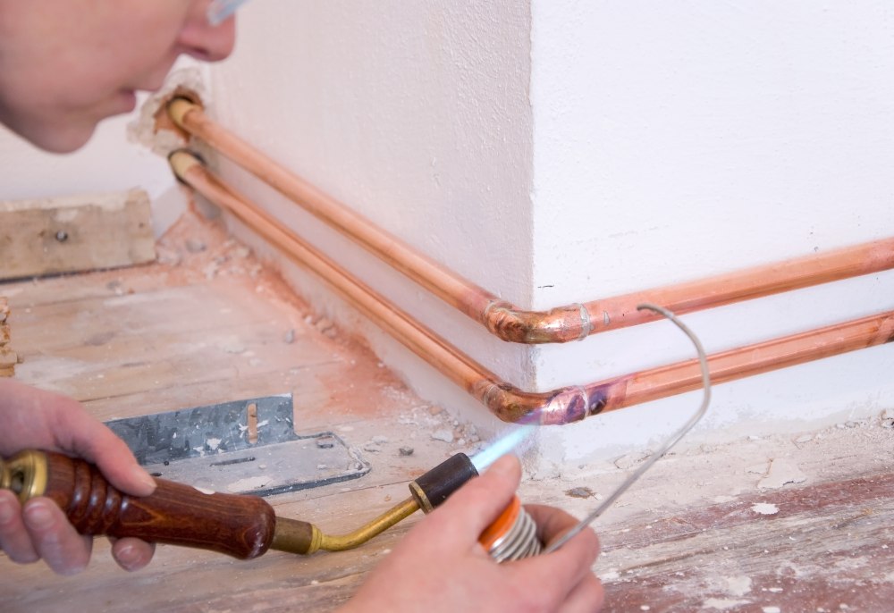 A man uses a torch to repair copper pipes in South Kansas City.